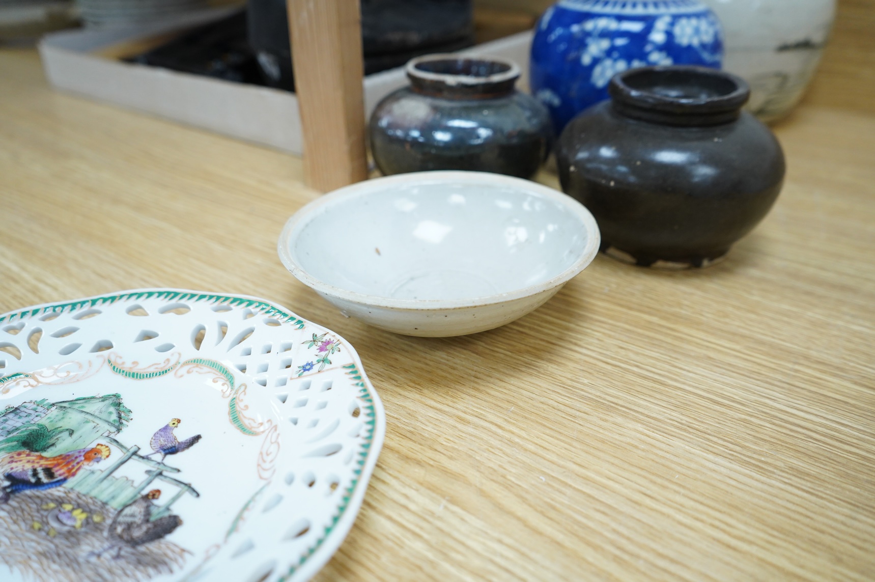 A collection of Chinese pottery jars and a decorated plate, tallest jar 18cm high
